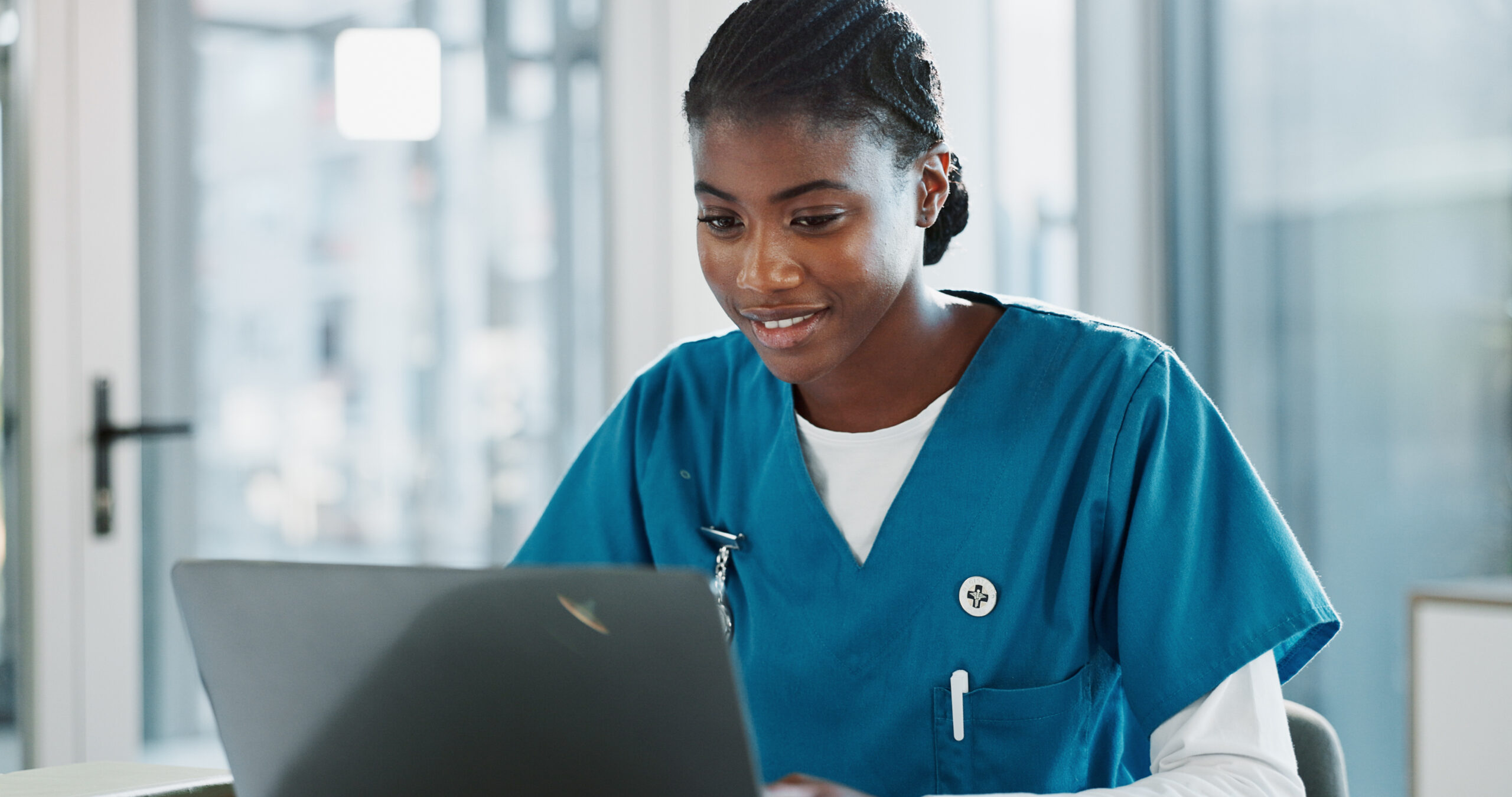 Clinic, doctor and black woman with laptop, typing and thinking with research, online reading and network. African person, medical or happy professional with computer, nurse or connection in hospital.